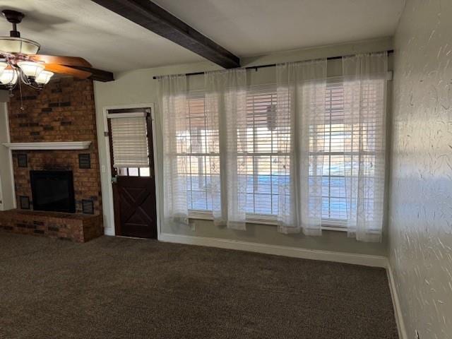 unfurnished living room featuring carpet, beam ceiling, a fireplace, a textured wall, and baseboards