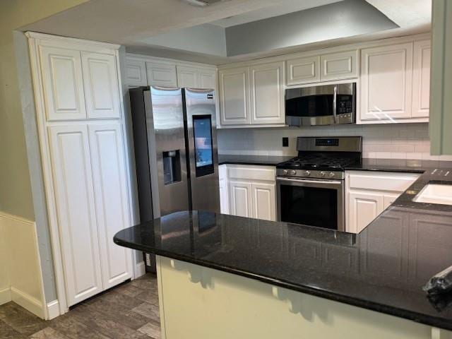 kitchen featuring appliances with stainless steel finishes, white cabinets, backsplash, and a peninsula