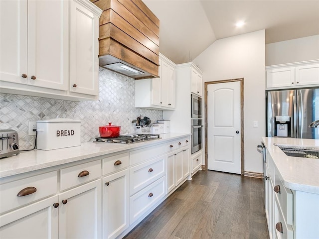 kitchen featuring white cabinetry, stainless steel appliances, light stone counters, vaulted ceiling, and custom exhaust hood