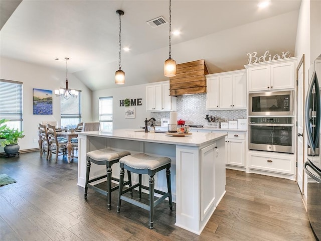 kitchen with a center island with sink, white cabinetry, lofted ceiling, and stainless steel appliances