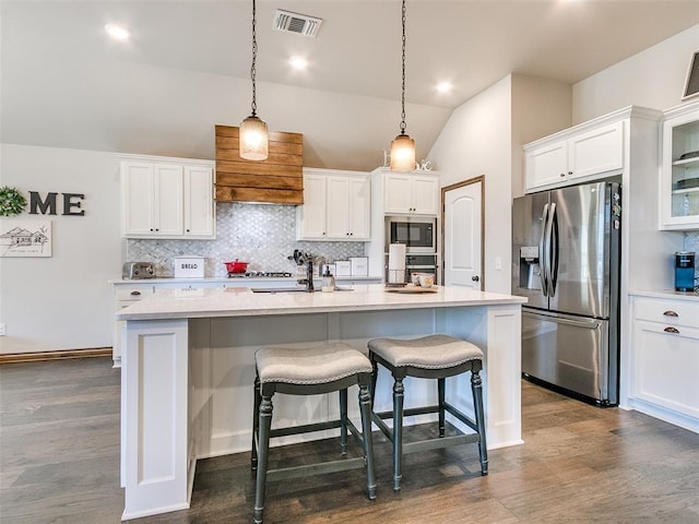 kitchen with pendant lighting, a center island with sink, stainless steel fridge with ice dispenser, built in microwave, and white cabinetry