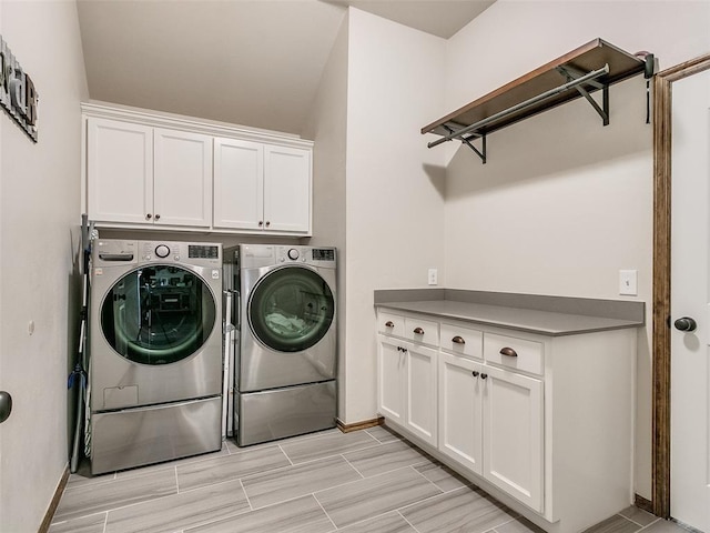 laundry area with washing machine and clothes dryer and cabinets