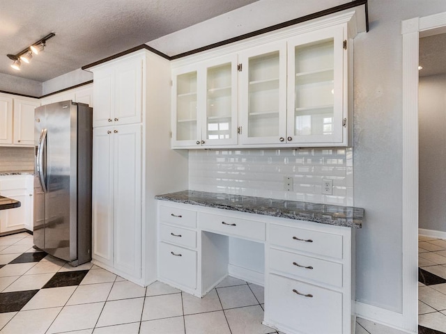 kitchen featuring stainless steel fridge, backsplash, dark stone countertops, a textured ceiling, and white cabinets