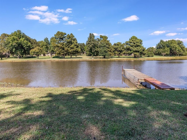 view of dock with a lawn and a water view