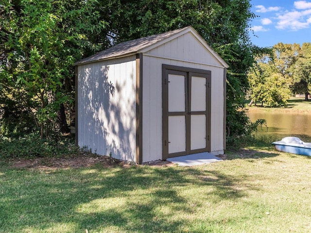 view of outbuilding featuring a lawn and a water view