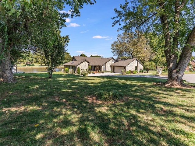 view of front facade with a garage, a front yard, and a water view