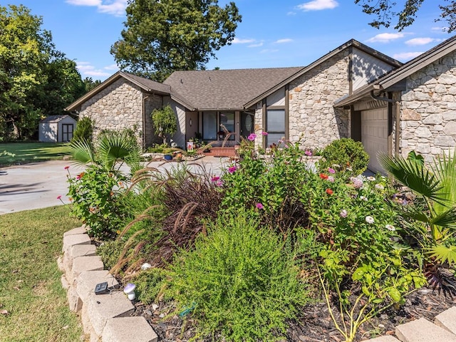 2207 Lake Front Cir, Norman, OK 73069 - view of front facade featuring stone siding, an attached garage, a storage shed, and driveway