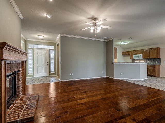 unfurnished living room with dark hardwood / wood-style flooring, a brick fireplace, ceiling fan, and crown molding