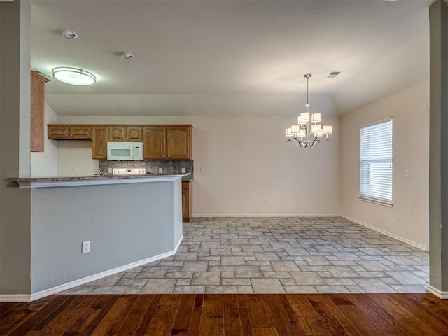 kitchen with decorative backsplash, kitchen peninsula, vaulted ceiling, decorative light fixtures, and a notable chandelier