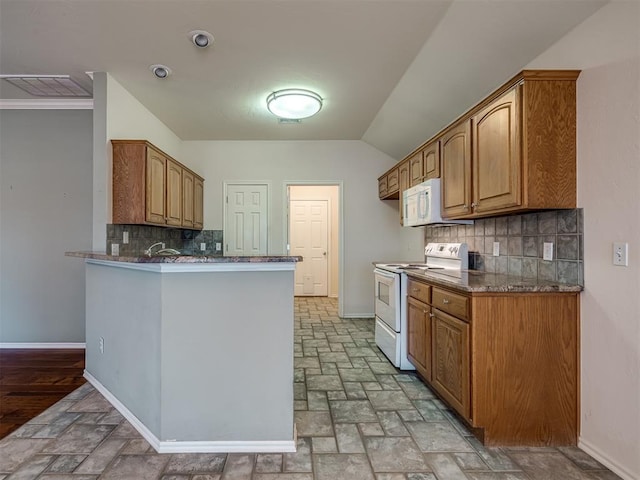 kitchen with kitchen peninsula, white appliances, dark stone countertops, and backsplash