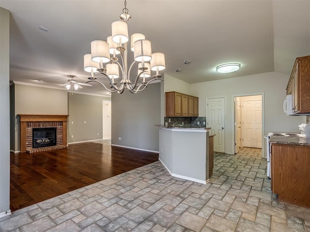 kitchen with stove, backsplash, ceiling fan with notable chandelier, hanging light fixtures, and a brick fireplace