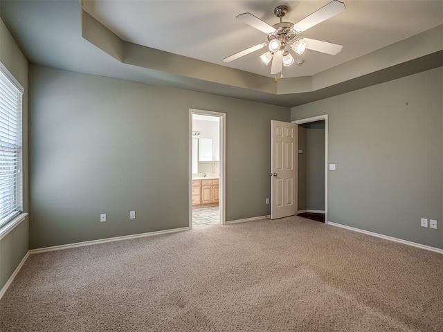 empty room featuring carpet flooring, ceiling fan, and a raised ceiling