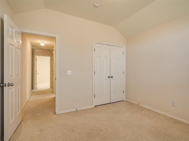 unfurnished bedroom featuring light colored carpet, lofted ceiling, and a closet