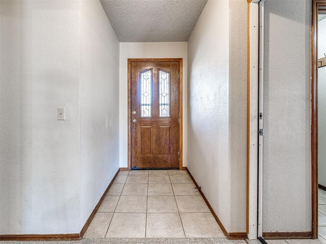 doorway to outside featuring light tile patterned floors and a textured ceiling