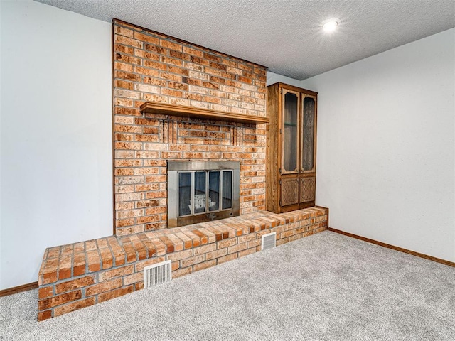 unfurnished living room with carpet flooring, a textured ceiling, and a brick fireplace