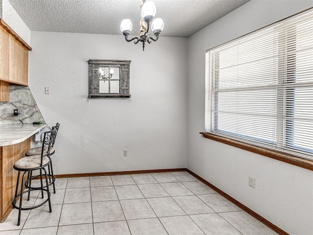 unfurnished dining area with light tile patterned floors, a textured ceiling, and an inviting chandelier