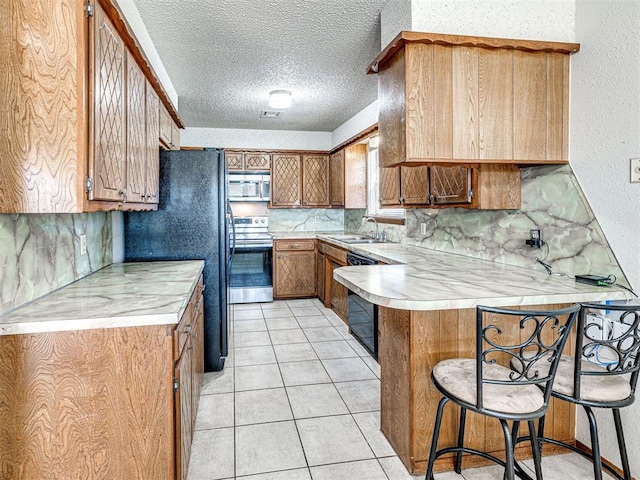 kitchen with kitchen peninsula, a kitchen breakfast bar, a textured ceiling, sink, and black appliances