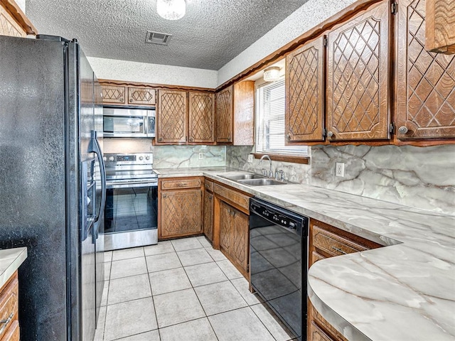 kitchen featuring backsplash, a textured ceiling, sink, black appliances, and light tile patterned floors