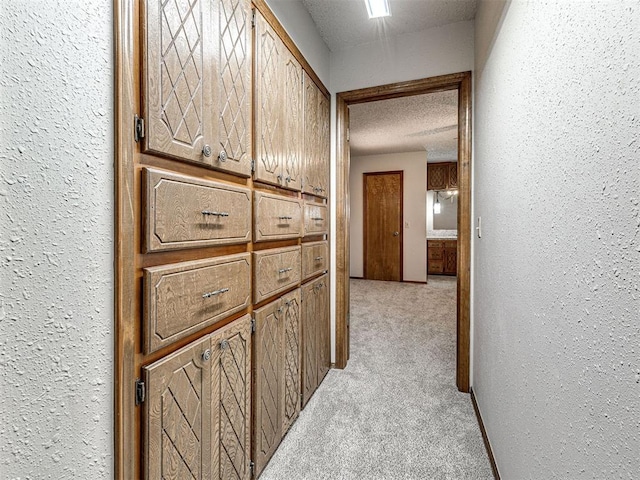 corridor with light carpet and a textured ceiling