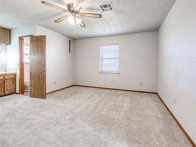 unfurnished bedroom featuring ensuite bathroom, ceiling fan, light colored carpet, and multiple windows