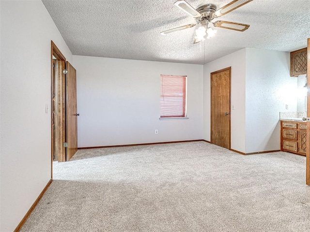 unfurnished bedroom featuring light carpet, a textured ceiling, and ceiling fan