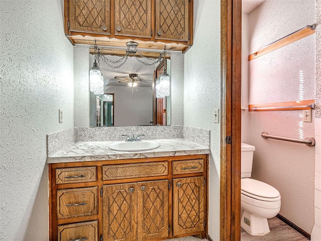 bathroom with ceiling fan, vanity, wood-type flooring, and toilet