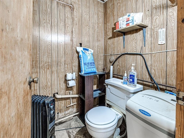 bathroom featuring toilet, radiator heating unit, and wooden walls