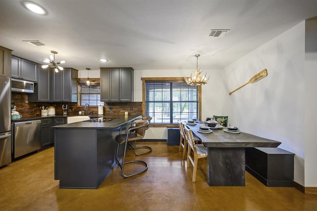 kitchen with a center island, stainless steel appliances, hanging light fixtures, and a notable chandelier