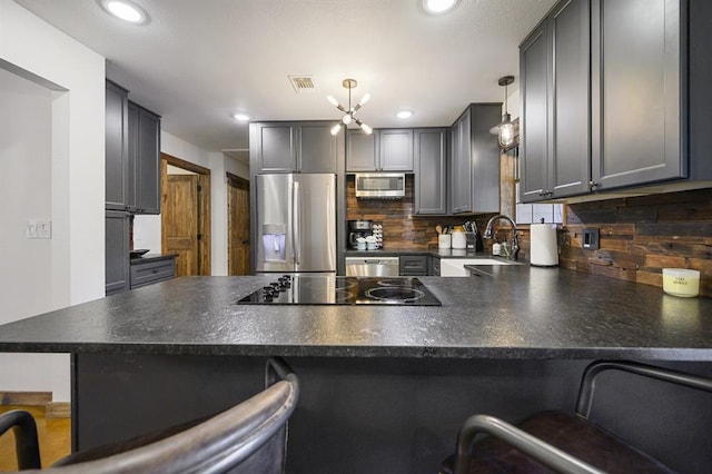 kitchen with kitchen peninsula, stainless steel appliances, sink, pendant lighting, and a breakfast bar area