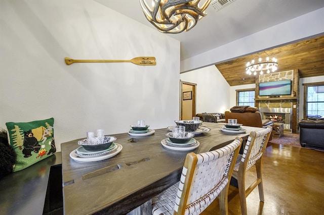 dining space with a stone fireplace, concrete floors, wooden ceiling, and vaulted ceiling