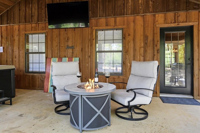 sitting room featuring wood walls, concrete floors, and lofted ceiling