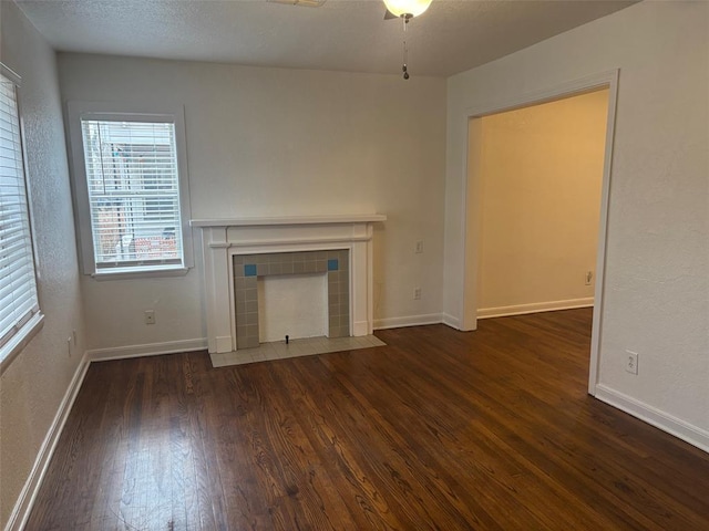 unfurnished living room with a fireplace, dark hardwood / wood-style floors, and ceiling fan