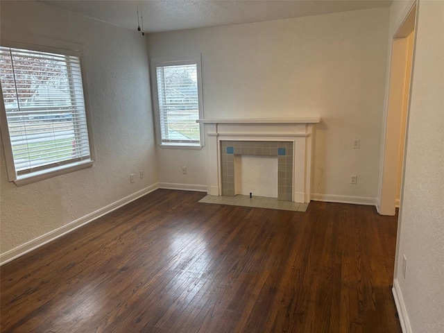 unfurnished living room with dark hardwood / wood-style floors and a tiled fireplace