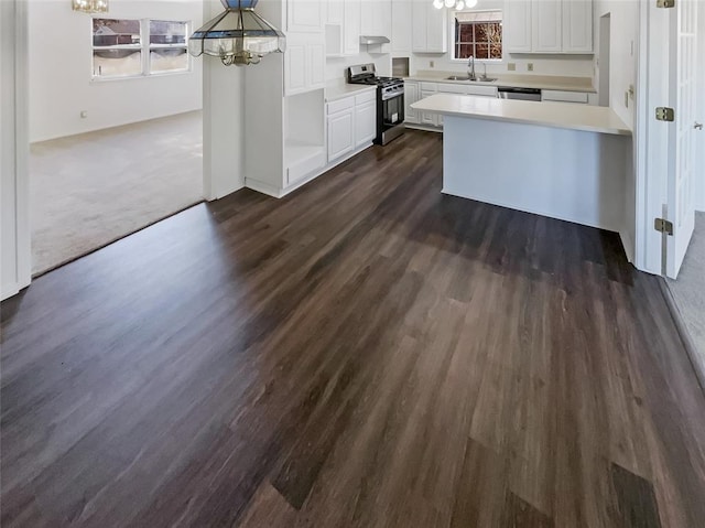 kitchen featuring gas range, white cabinetry, sink, an inviting chandelier, and pendant lighting