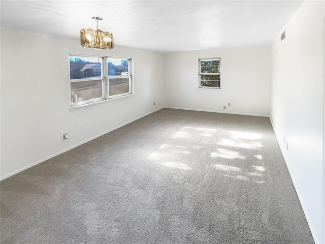 carpeted empty room featuring an inviting chandelier