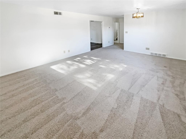 unfurnished room featuring carpet and a notable chandelier