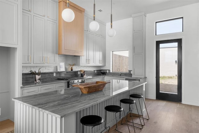 kitchen featuring white cabinets, high end stainless steel range oven, decorative light fixtures, and a kitchen island