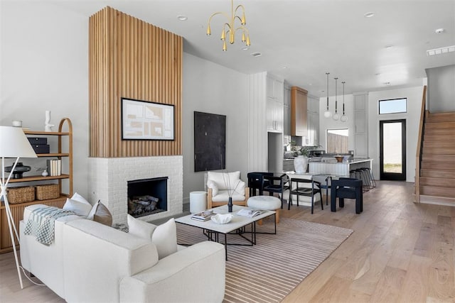 living room featuring light hardwood / wood-style floors, a notable chandelier, and a brick fireplace