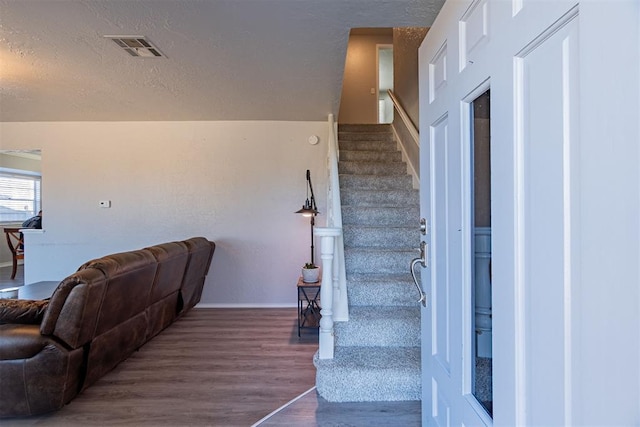 stairs with a textured ceiling and hardwood / wood-style flooring