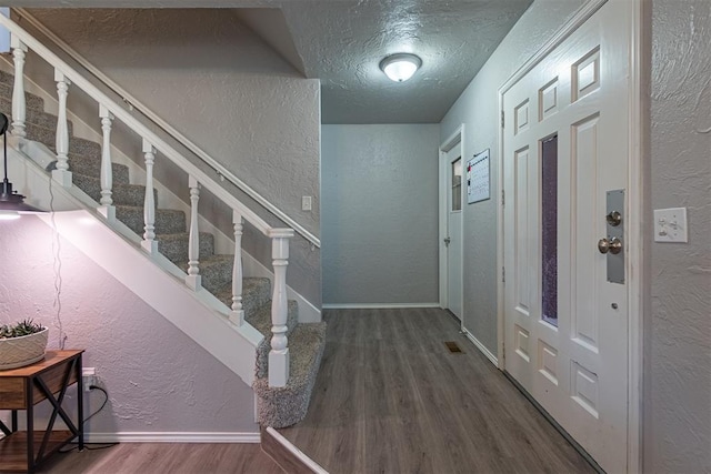 entrance foyer with a textured ceiling and dark hardwood / wood-style floors