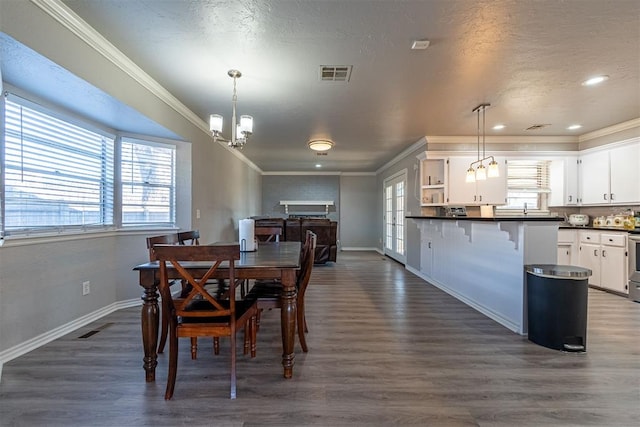 dining area with dark hardwood / wood-style flooring, an inviting chandelier, a textured ceiling, and ornamental molding