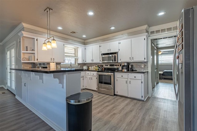 kitchen featuring kitchen peninsula, stainless steel appliances, white cabinetry, and a breakfast bar area