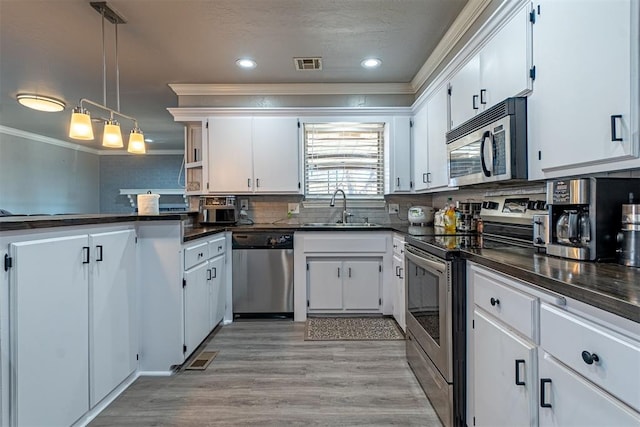 kitchen featuring white cabinetry, sink, pendant lighting, appliances with stainless steel finishes, and ornamental molding