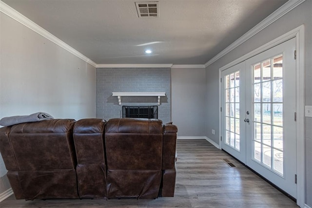 living room with french doors, dark hardwood / wood-style flooring, a brick fireplace, and crown molding