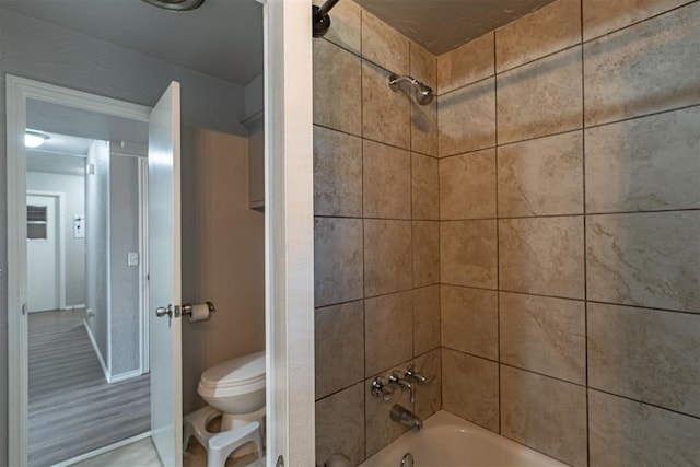 bathroom featuring toilet and tiled shower / bath