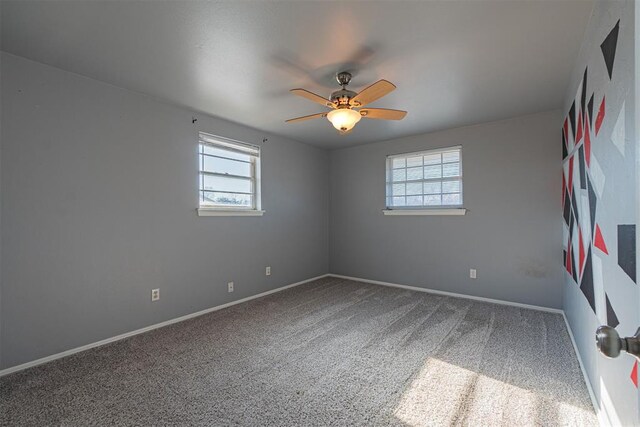 carpeted spare room featuring ceiling fan and a healthy amount of sunlight