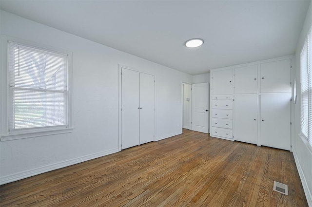 unfurnished bedroom with hardwood / wood-style flooring and multiple windows