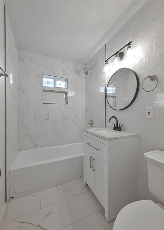 full bathroom with tiled shower / bath combo, toilet, and vanity