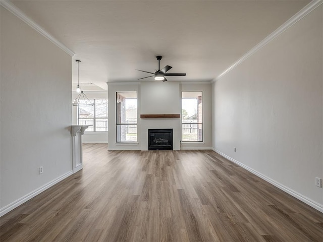 unfurnished living room with dark hardwood / wood-style flooring, a wealth of natural light, crown molding, and ceiling fan