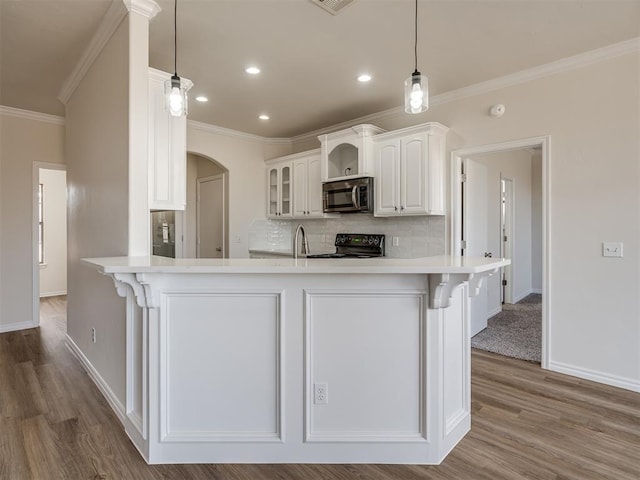 kitchen featuring light hardwood / wood-style flooring, white cabinetry, hanging light fixtures, and black range oven